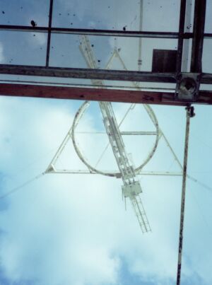 Suspended platform as seen looking up from under the center of the reflective dish; partly through the small, permanent rectangular opening, partly right through the reflecting surface;